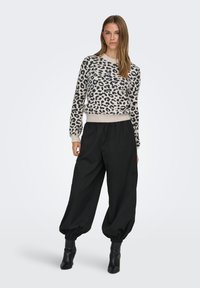 Leopardimustriga kreemis ja mustas toonis kootud kampsun, millele on lisatud laiad mustad püksid ja pahkluud katvad saapad. Lihtne, kaasaegne disain.