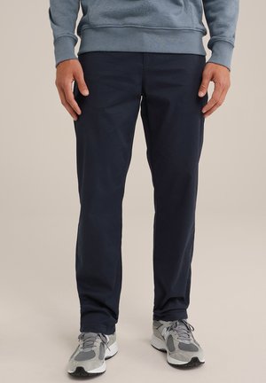 Pantalones de algodón azul marino con un diseño de pierna recta, combinados con zapatillas grises que presentan detalles de malla y ante.