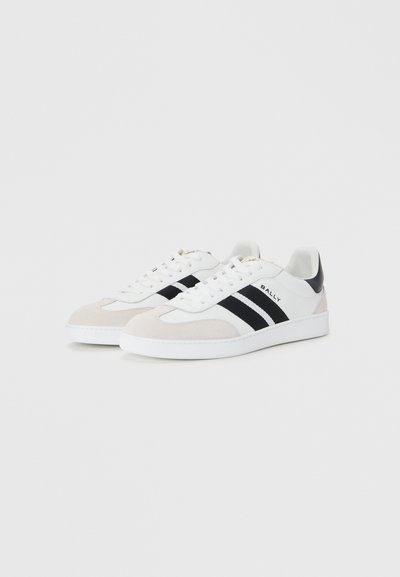 Adidași albi cu accente din suede gri și dungi negre. Prezintă o textură netedă, vârf rotund și talpă din cauciuc plat. Branding "BALLY" pe lateral.