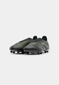 Zwarte voetbalschoenen met een gladde textuur, voorzien van groene gebogen strepen en een laag profiel. Rond neus en met studs op de zool.