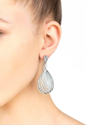 Silver teardrop earrings featuring a spiral design, adorned with clear crystals and a textured finish, showcased on a model's ear.