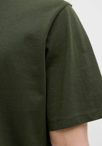 Mørkegrøn kortærmet t-shirt lavet af bomuld, med en glat tekstur og en klassisk rund halsudskæring med subtile syninger.