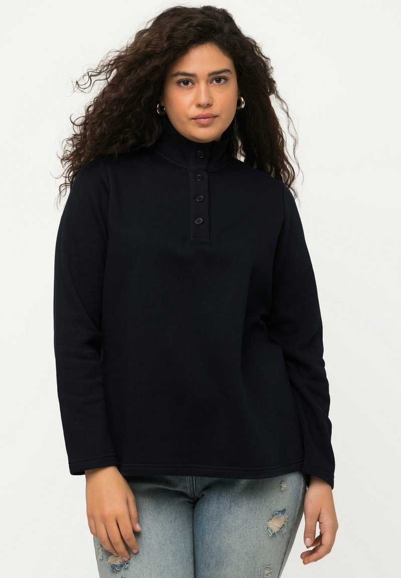 Pullover lungo blu navy a maniche lunghe con colletto alto, patta con bottoni e tessuto morbido. Presenta una vestibilità rilassata e dettagli di cucitura discreti.
