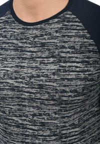 Tumesinine ja halli triibuline T-särk tekstuuriga, ümara kaela ja lühikeste raglanvarrukatega, mis on ühtlaselt tumesinised.