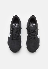 Black Nike sneakers with a textured upper, white Swoosh logo, and black laces. Features a rounded toe and cushioned sole.