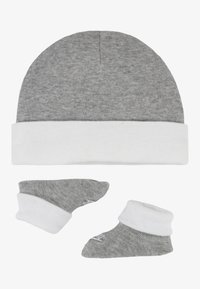 Cappello di cotone grigio con risvolto bianco, abbinato a due calzini grigi e bianchi con un design del risvolto simile, texture morbida.