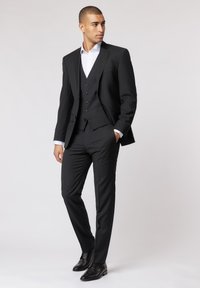 Dunkelgrau Anzug mit drei Teilen, mit Reverskragen, fünf Knöpfen, slim fit Hose und schwarzen Dressschuhen, kombiniert mit einem weißen Hemd.