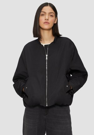 Giubbotto bomber nero con chiusura a zip, colletto rialzato e tasche laterali. Realizzato in tessuto liscio con una vestibilità leggermente oversize.