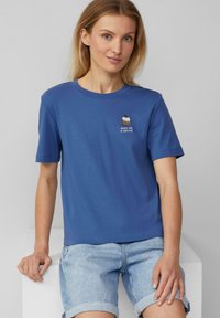 T-shirt en coton bleu à manches courtes, présentant un design de cupcake brodé avec le texte "DOUX COMME UN CUPCAKE" au-dessus.