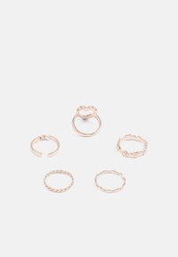 Cinco delicados anéis de ouro com diferentes desenhos, incluindo uma forma de coração, banda torcida, banda aberta, banda ondulada e pequenas incrustações em forma de coração.