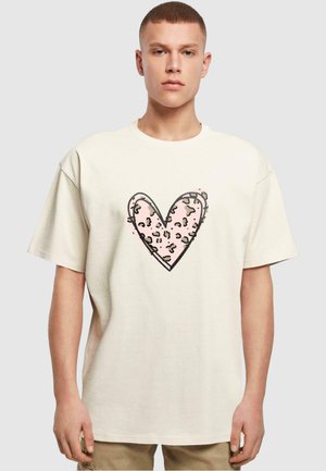 Cremefarvet bomulds-T-shirt med et stort pink hjerte designet med en sort kontur og leopardmønster i midten. Korte ærmer.