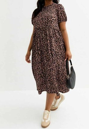 Kvinde iført en brun og sort leopardprint midi kjole med pufærmer, hvide og beige sneakers og med en sort håndtaske.