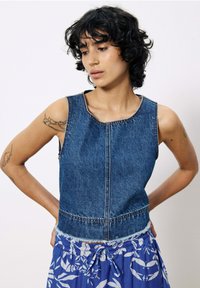 Mouwloos denim top, medium blauw, met een ronde halslijn en een cropped ontwerp. Zichtbare stiksels accentueren de naden.