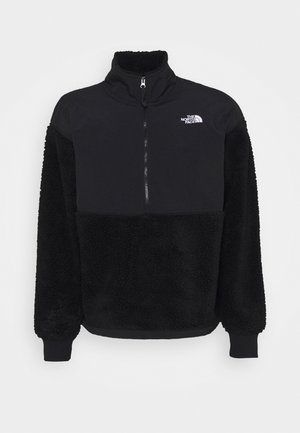 Zwart half-zip pullover gemaakt van gladde stof aan de bovenkant en fuzzy textuurmateriaal aan de onderkant, met ribgebreide manchetten en geborduurd logo.
