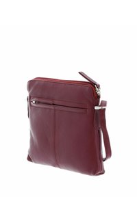 Sac à bandoulière en cuir rouge avec fermeture éclair, forme rectangulaire élégante et poche avant. Équipé d'une sangle ajustable et de quincaillerie en acier inoxydable.