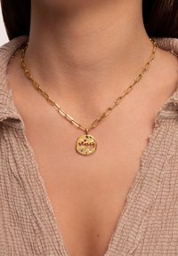 Collar de cadena dorada con un colgante circular texturizado grabado con "MAMA", que presenta acentos de piedras preciosas de colores.