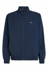 Námořnická modrá lehká bunda s vysokým límcem, zapínáním na zip, elastickými manžetami a dvěma bočními kapsami. Na hrudi se nachází malé logo.