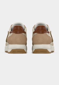 Ζευγάρι μπεζ και καφέ αθλητικά παπούτσια, εμφανιζόμενα από πίσω, με το «LOVE MOSCHINO» χαραγμένο στις μπεζ σόλες.