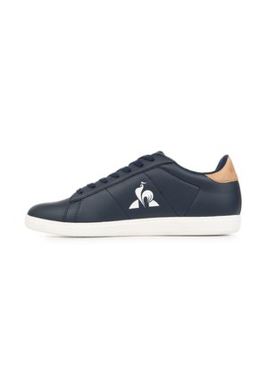 Marineblauer Sneaker in Low-Top-Design mit weißer Sohle, Schnürverschluss, braunem Fersenlasche und weißem stilisiertem Vogel-Logo an der Seite.
