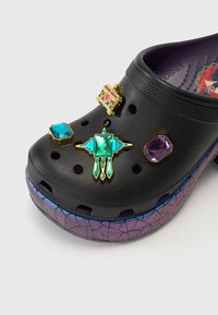 Czarne Crocsy z kolorowymi ozdobami w postaci klejnotów, w tym turkusowych i purpurowych kamieni, z teksturowaną, wielokolorową irydyscencyjną podeszwą.