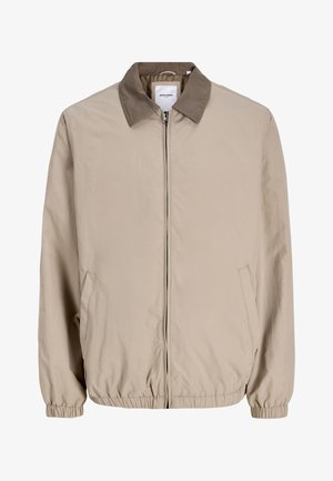 Šviesiai rudos spalvos striukė su užtrauktuku, elastinėmis rankogalių ir apačios juostelėmis, kontrastingu rudos spalvos apykakle ir šoninėmis kišenėmis.