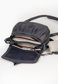 Zaino in pelle blu scuro, con parte superiore arricciata, molteplici scomparti, fodera a strisce e chiusure a zip. Texture liscia con hardware discreto.