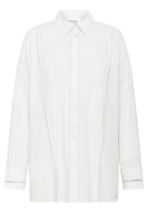 Balta garām piedurknēm krekls, kas izgatavots no viegla auduma, ar pogu aizdari, klasisku apkakli un dekoratīvām šuvēm sānos.