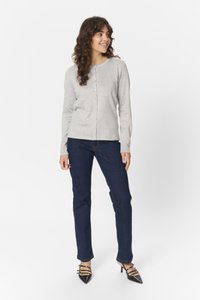 Šedý žebrovaný kardigan s dlouhým rukávem a zapínáním na knoflíky, spárovaný s tmavě modrými rovnými džíny a černými lodičkami s špičatou špičkou.