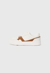 White sneaker with brown suede accents, featuring a textured finish, round toe, thick sole, and traditional lace-up design.