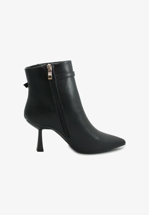 Stivale alla caviglia in pelle nera con punta affilata, cerniera laterale e tacco a stiletto. Presenta una texture liscia e accenti di design minimalisti.