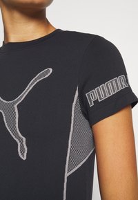 Svart kortärmad t-shirt med Puma-logotyp. Har nättextur och detaljer längs sidorna. Rund halsringning med en figurnära design.