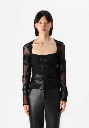 Black long-sleeve top with a square neckline, featuring floral embroidery on sheer fabric, layered over a solid black base.
