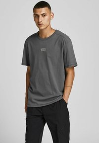 Szara bawełniana koszulka z krótkim rękawem i okrągłym dekoltem. Posiada małe białe logo "JACK & JONES" na piersi. Gładka tekstura.