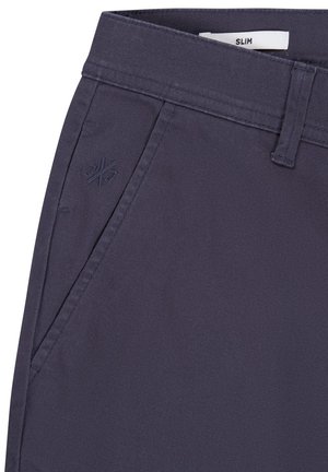 Pantalones navy de corte slim fabricados con una tela suave, que cuentan con bolsillos laterales y un sutil logo bordado en la parte frontal.