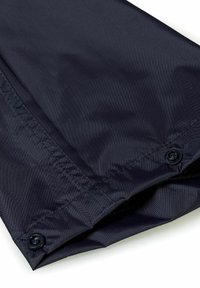 Donkerblauwe stof, gladde textuur, met gestikte naden en twee donkere knopen aan de zoom. Lichtgewicht materiaal, geschikt voor bovenkleding.
