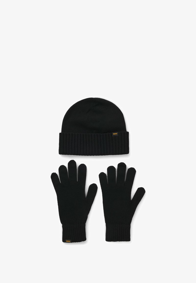 Svart strumpmössa och handskuppsättning. Ribbad textur, mjukt material, med en liten gul logotyp på båda föremålen. Klassisk design, varm och mångsidig.