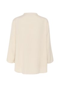 Camicia over-size beige chiaro con collo rotondo e maniche a tre quarti, caratterizzata da una texture liscia e un design leggero e fluttuante.
