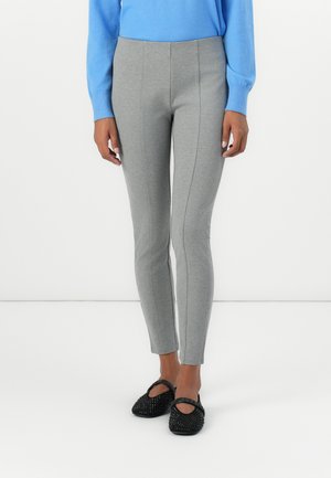 Grå tights med en tettsittende design, med sidesøm, satt sammen med svarte dekorative leiligheter og en lyseblå langermet topp.