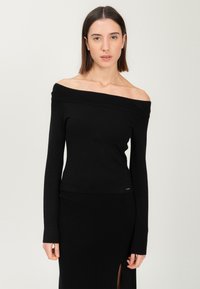 Top nero a spalle scoperte con colletto a coste, maniche lunghe e design aderente. Tessuto liscio e logo dorato accentato sull'orlo.