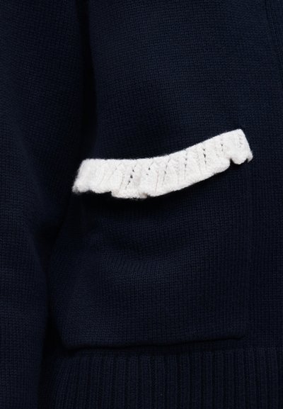 Σκούρο ναυτικό πλεκτό ύφασμα με μικρή λευκή οριζόντια βολάν διακοσμητική λεπτομέρεια στη μέση.