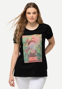 T-shirt in cotone nero con una stampa grafica colorata di una scena di spiaggia con foglie di palma e testo, rifinita con maniche corte.