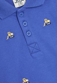 Polo shirt in cotone blu con tre bottoni blu, presenta motivi ricamati di escavatori gialli e neri sul davanti e un colletto a costine.