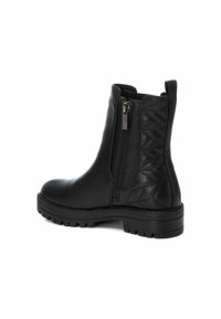 Botín negro de cuero hasta el tobillo que cuenta con un zipper lateral, parte trasera texturizada con patrón de zigzag, puntera redondeada y suela rugosa para tracción.