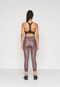 Αθλητικό σουτιέν σε μαύρο χρώμα, συνδυασμένο με ψηλόμεσα κολάν που διαθέτουν καφέ λεοπαρ σχέδιο. Το σύνολο προσφέρει εφαρμοστό σχέδιο και αδιάκοπη κατασκευή.