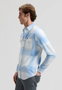 Πουκάμισο με μακριά μανίκια και καρό σχέδιο σε ανοιχτό γαλάζιο και λευκό, κατασκευασμένο από ύφασμα με λεία υφή. Διαθέτει δύο τσέπες στο στήθος και κλείσιμο με κουμπιά.