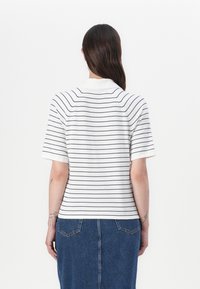 Rutet hvit og marineblå polo skjorte med korte ermer og krage, stylet med et blått denimskjørt. Myk stoff og avslappet passform.