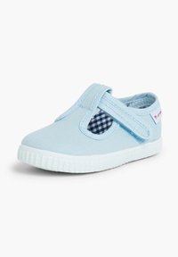 Zapato slip-on de lona azul con una banda elástica, panel a cuadros y suela de goma blanca. Presenta una textura suave y un diseño de punta redonda.