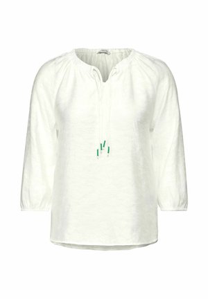 Blouse en lin blanc avec des manches longues, un col froncé et des liens ajustables présentant des accents verts. Coupe légèrement ample avec un ourlet arrondi.
