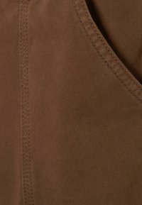 Bruine stof met een soepele textuur, voorzien van een diagonale ribbelpatroon en zichtbare stiksels langs de randen.