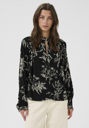 Blusa nera con ricamo floreale bianco, maniche lunghe, scollo a chiave con dettaglio in bottone e accenti arricciati ai polsini.